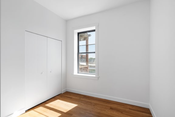 a room with white walls and a window and wooden floors