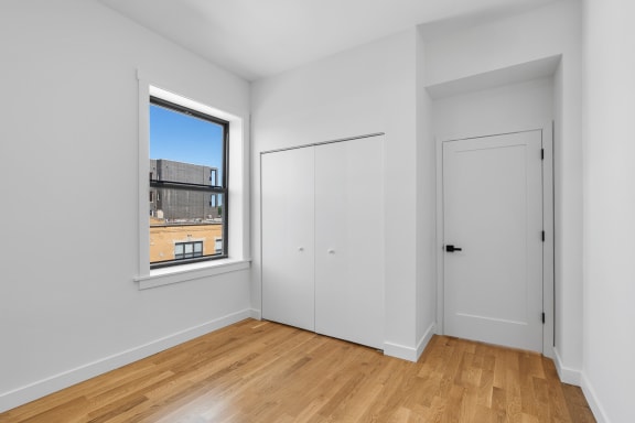 a bedroom with white walls and a window and a door