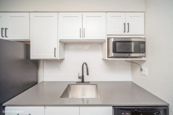 a kitchen with white cabinets and a microwave in it
