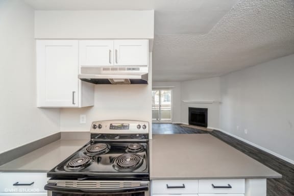 an empty kitchen with white cabinets and a stove top oven