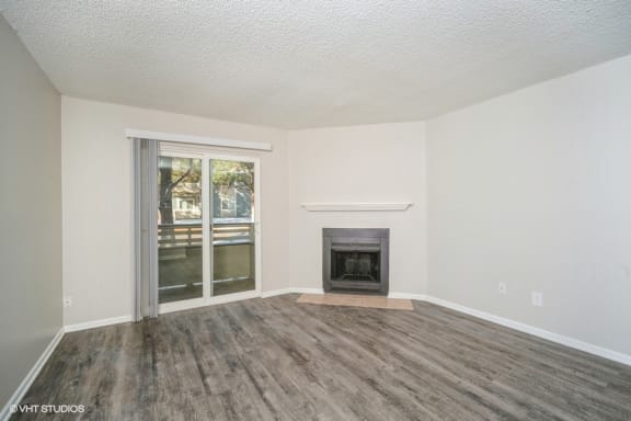 an empty living room with a fireplace and a sliding glass door