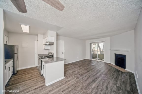 an empty living room with a kitchen and a fireplace