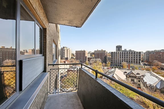 A balcony with a metal railing overlooks a cityscape.