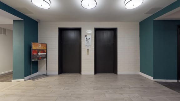 two black doors in a room with a tile floor and blue walls
