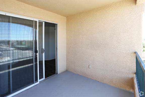 A balcony with a sliding glass door and a beige wall.