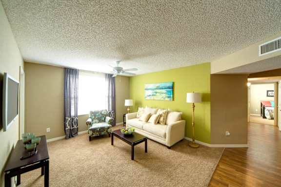 A living room with a white couch and a painting on the wall.