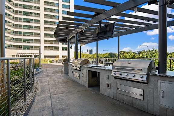 A patio with a grill and a building in the background.