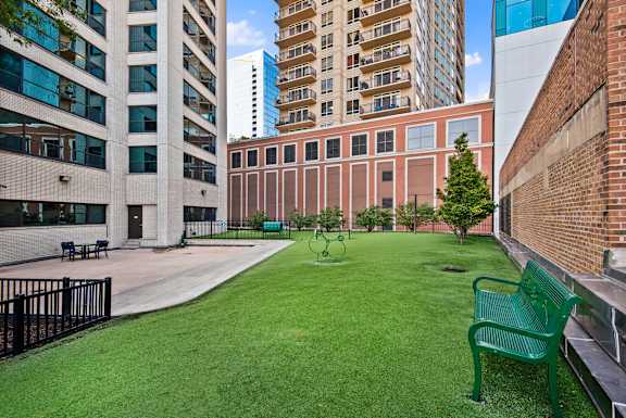 A green bench sits in a grassy courtyard.