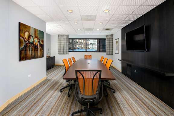 A conference room with a long table and orange chairs.