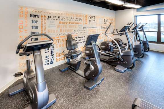 A gym with a wall of inspirational quotes and exercise equipment.