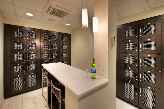 A wine bottle and two glasses are on a counter in a room with dark brown cabinets.