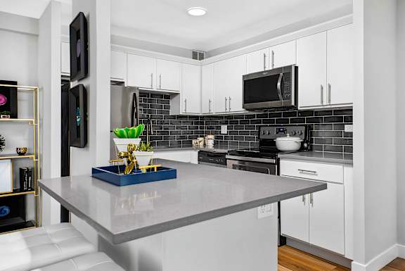 A modern kitchen with a grey countertop and white cabinets.