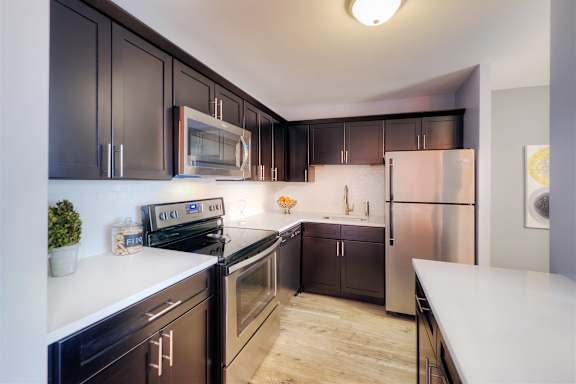 A modern kitchen with dark brown cabinets and stainless steel appliances.
