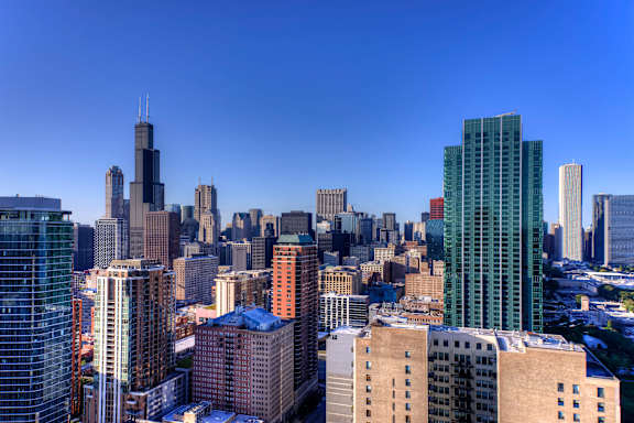 A cityscape with a mix of modern and older buildings under a clear blue sky.