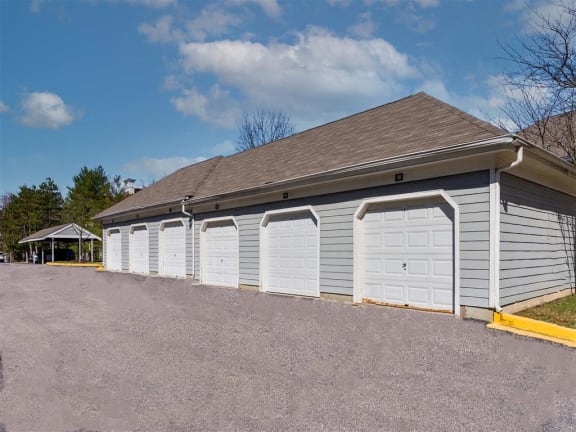 a row of white garages with doors on the side of a parking lot
