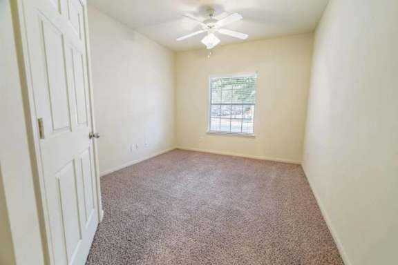 A room with a carpeted floor and a ceiling fan.