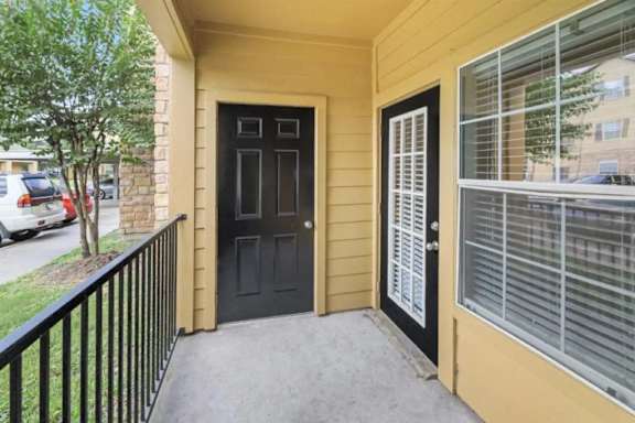 A black door is on the left side of a tan building.