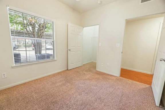 A room with a carpeted floor and a window with blinds.