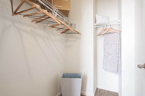 A white wall with a wooden hanger and a white trash can.