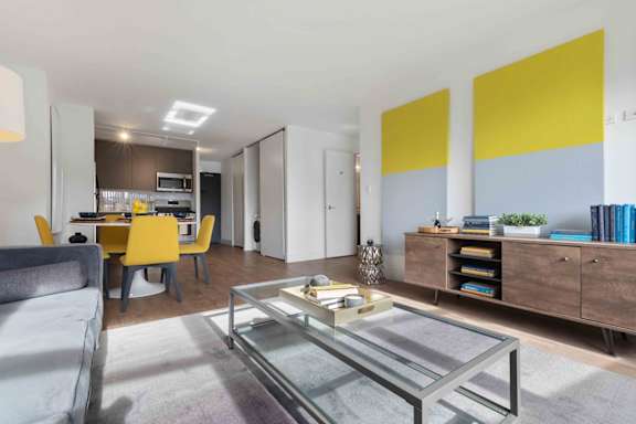 A modern living room with a glass coffee table and yellow chairs.