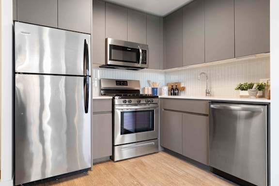 A modern kitchen with stainless steel appliances and wooden flooring.