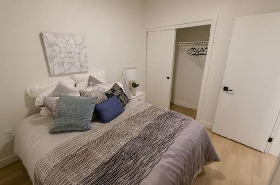 A bedroom with a bed, pillows, a lamp, and a painting on the wall.