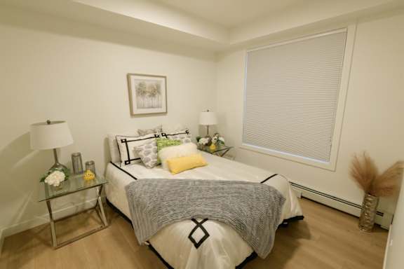 A bedroom with a bed, two lamps, a nightstand, and a picture on the wall.