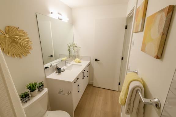A bathroom with a white vanity and a yellow towel.