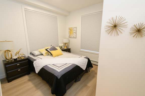 A bedroom with a bed, nightstand, and two wall decorations.