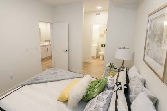 A bedroom with a bed, lamp, and painting on the wall.