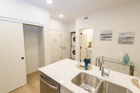 A kitchen with a white counter top and a stainless steel sink.