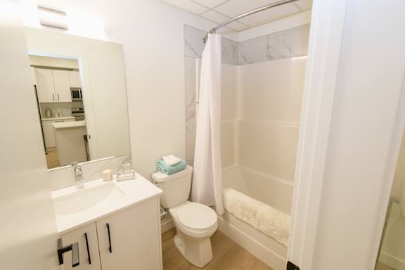 A white bathroom with a toilet, sink, and shower.