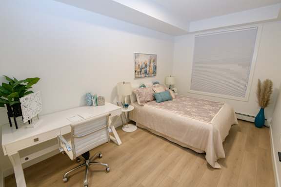 A bedroom with a bed, desk, and chair.