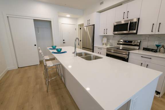 A kitchen with white countertops and stainless steel appliances.