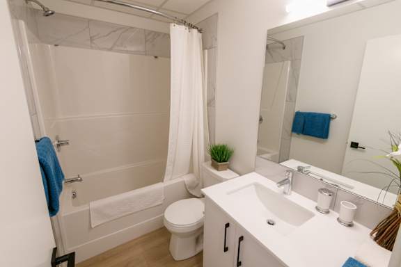 A white bathroom with a white toilet, sink, and bathtub.