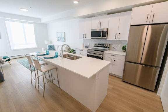 A modern kitchen with a white island and stainless steel appliances.