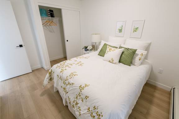 A bed with a white comforter and green pillows in a room with a white door.