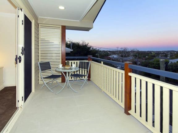 a balcony with a table and chairs and a view of the sunset
