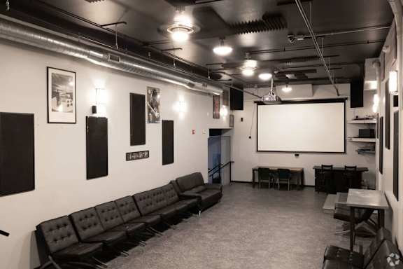 A black leather couch is situated in a room with a white screen and a black table.
