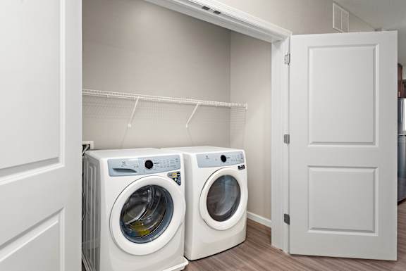 Two white front load washing machines in a laundry room.