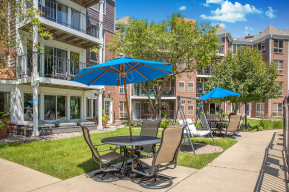 a patio with tables and chairs and umbrellas in front of an apartment building