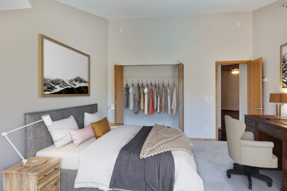 a bedroom with a bed and a closet with clothes on it