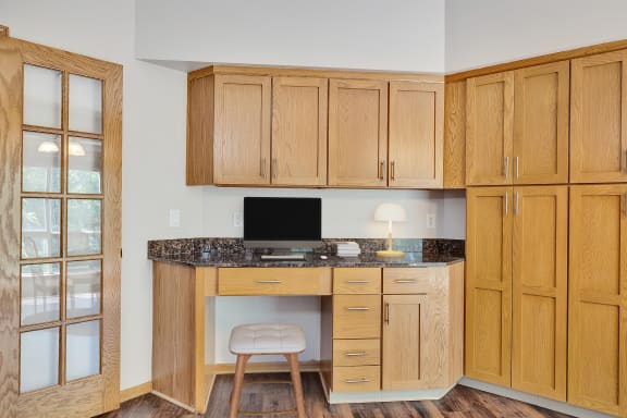 a home office with wooden cabinets and a desk with a computer