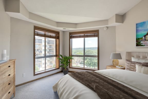 the master bedroom has a large window and a comfy bed