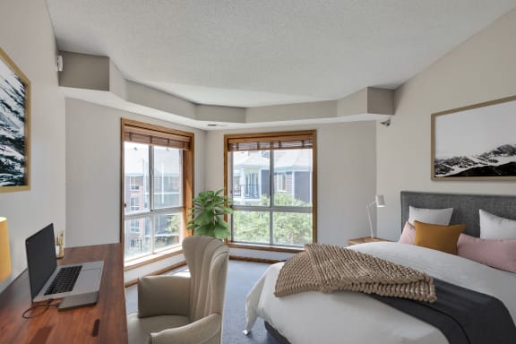 a bedroom with a bed and a laptop on a desk