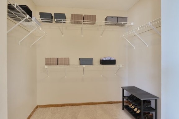 a walk in closet with shelves and a rack on the wall