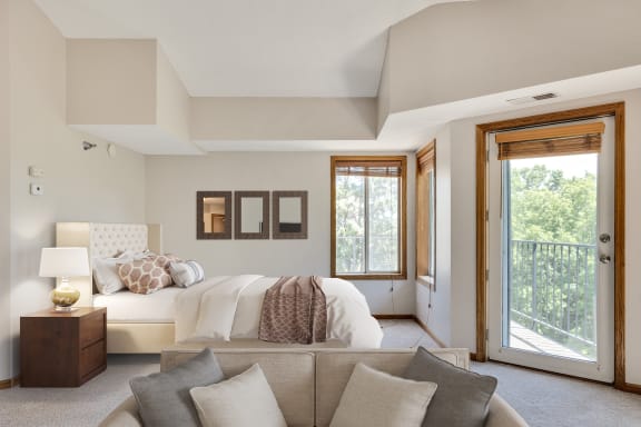 a bedroom with a bed and a couch and a door to a balcony