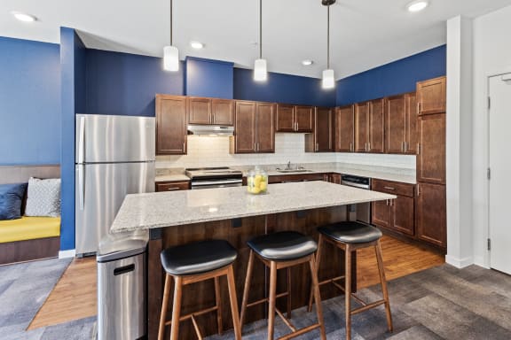 a kitchen with a large island with three stools at EastGate Apartments, Rochester, Minnesota