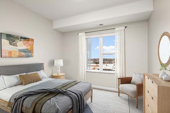 A bedroom with a bed, chair, and a painting on the wall.