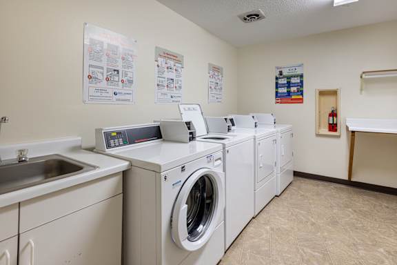 a washer and dryer facility with laundry machines and a sink at Heritage Hills Apartments, Minnesota